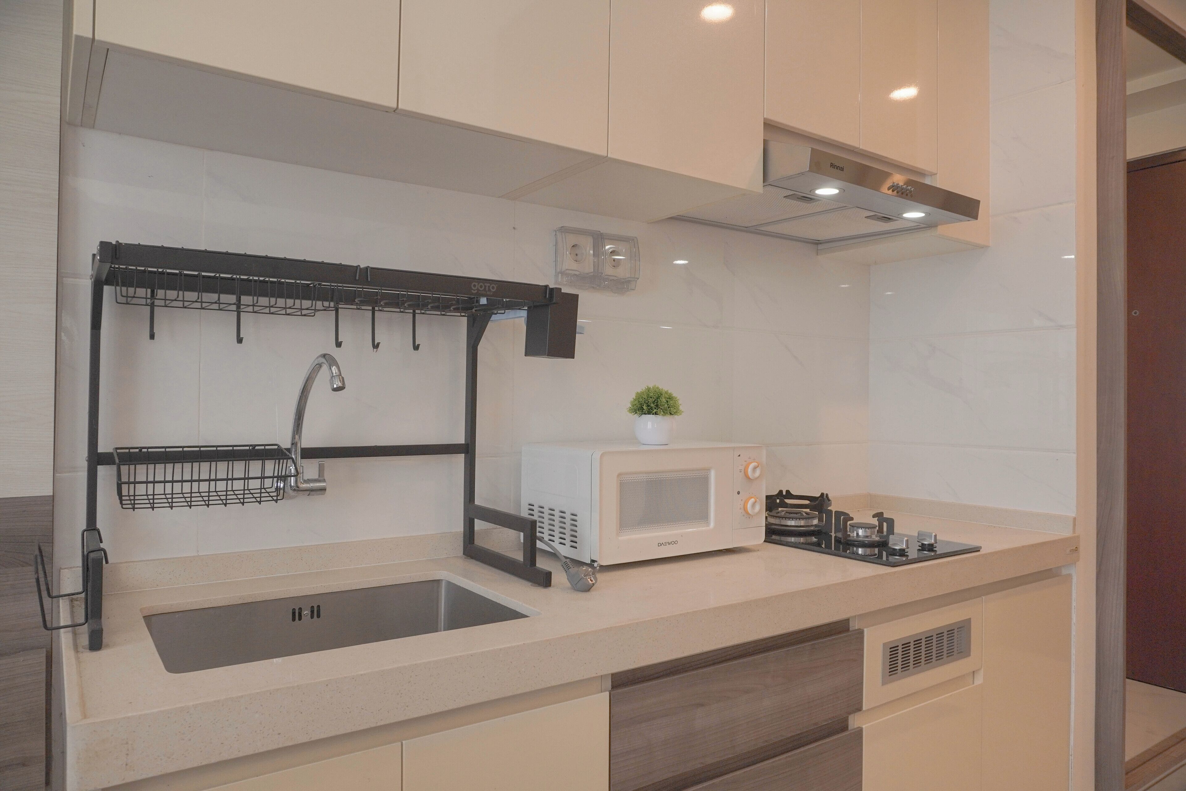 A modern kitchen with a built-in microwave, a sink with a faucet, and a small potted plant on the counter.