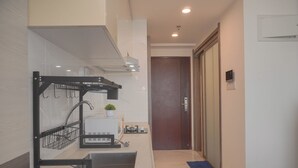 A modern kitchen with a built-in sink, a black metal rack, and a small potted plant. - Best Choice And Cozy Studio Sky House Bsd Apartment (Pagedangan)