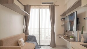 A modern living room with a sofa, a flat-screen TV, and a dining area with a table and chairs. - Best Choice And Cozy Studio Sky House Bsd Apartment (Pagedangan)