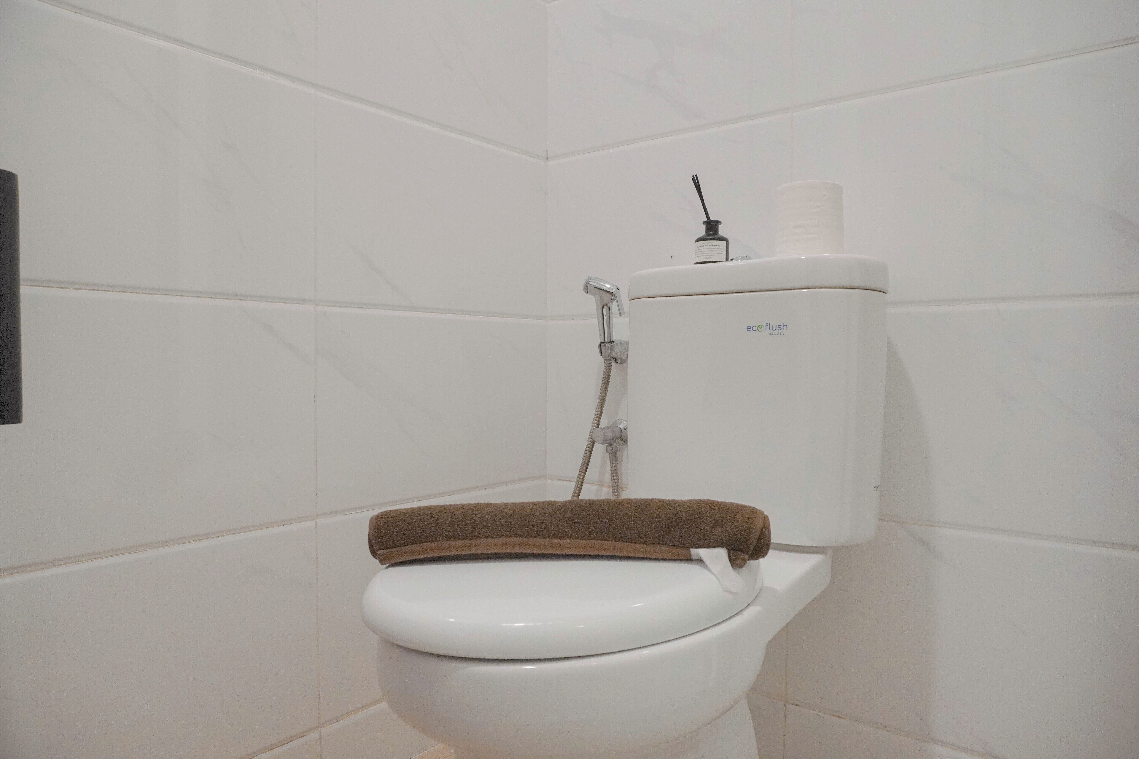 Eine weiße Toilette mit braunem Deckel, Spülhebel und Toilettenpapierhalter.
