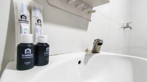 A bathroom with a white sink, two bottles of travelio shampoo, and a faucet. - Restful And Tidy Studio At Paltrow City Apartment (Semarang)
