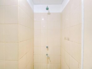 Un baño pequeño con revestimiento de azulejos, una lámpara en el techo y dos grifos.