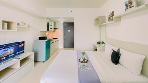 Habitación de hotel con cama, televisión, kitchenette y baño.