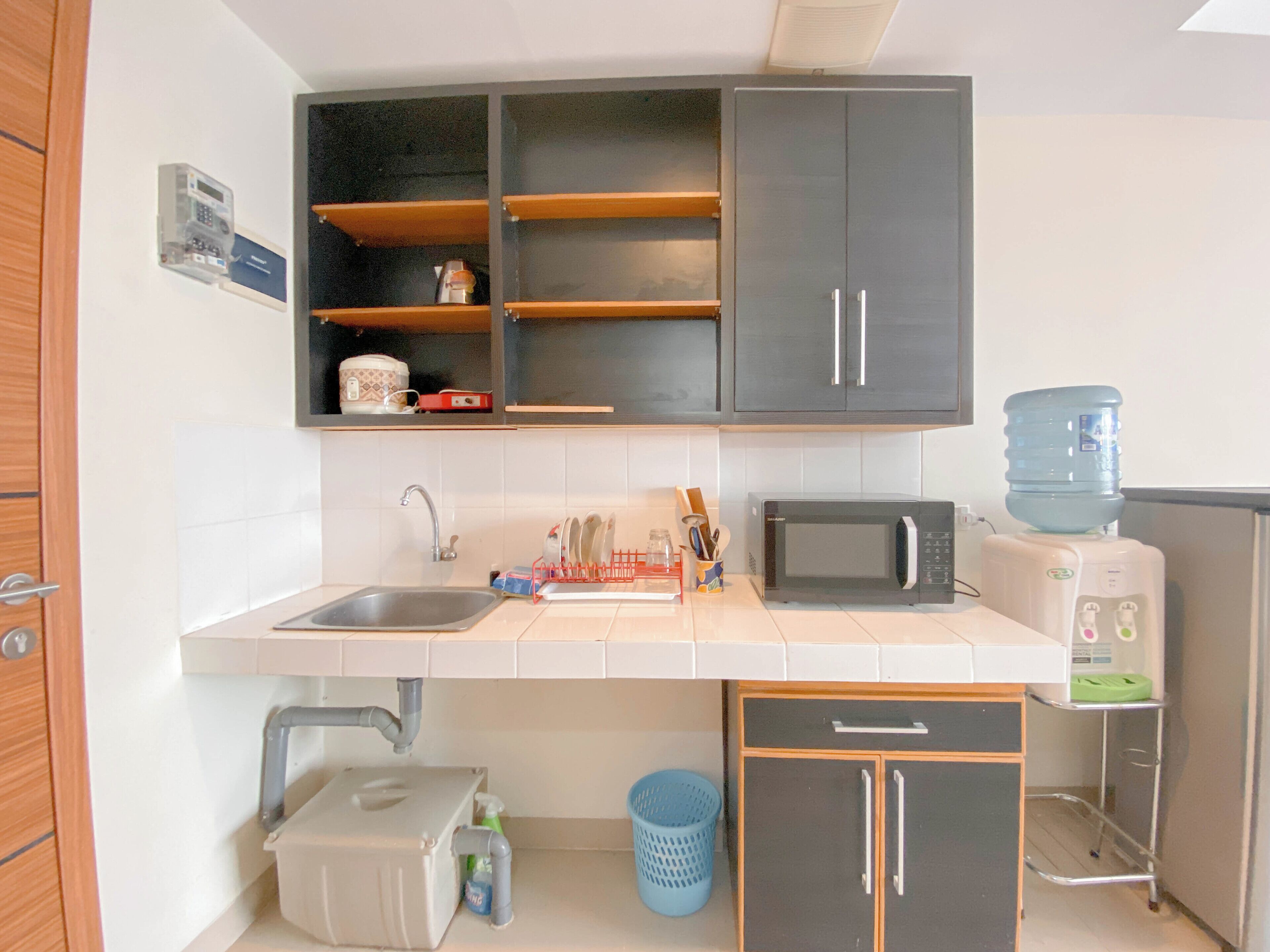 Een kleine keuken met een spoelbak, magnetron en een waterdispenser.