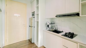 Una cocina compacta con armarios blancos, microondas integrado, estufa a gas y pileta de acero inoxidable.