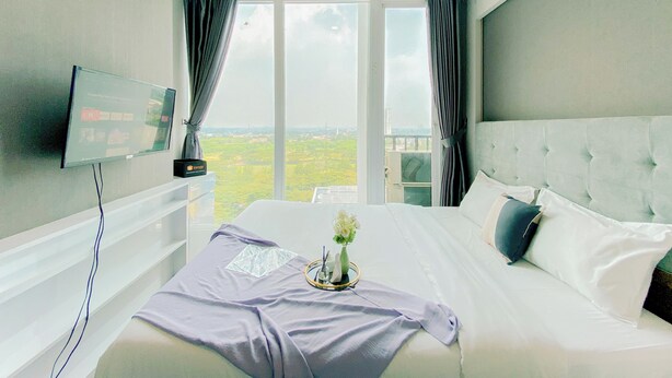 Habitación de hotel con una cama grande, un televisor de pantalla plana montado en la pared y vistas al campo a través de las ventanas.