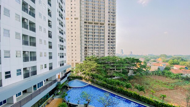A high-rise building with multiple balconies and a rooftop pool area with surrounding greenery. - Nice Studio At Parkland Avenue Apartment (South Tangerang)