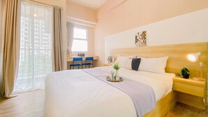 A hotel room with a bed, a desk, a chair, a nightstand, and a window with curtains. - Nice Studio At Parkland Avenue Apartment (South Tangerang)
