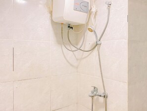 Un bagno con doccia, termosifone a parete e pannello di controllo.