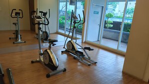 An indoor gym with exercise equipment, large windows, and a wooden floor. - Nice Studio At Parkland Avenue Apartment (South Tangerang)