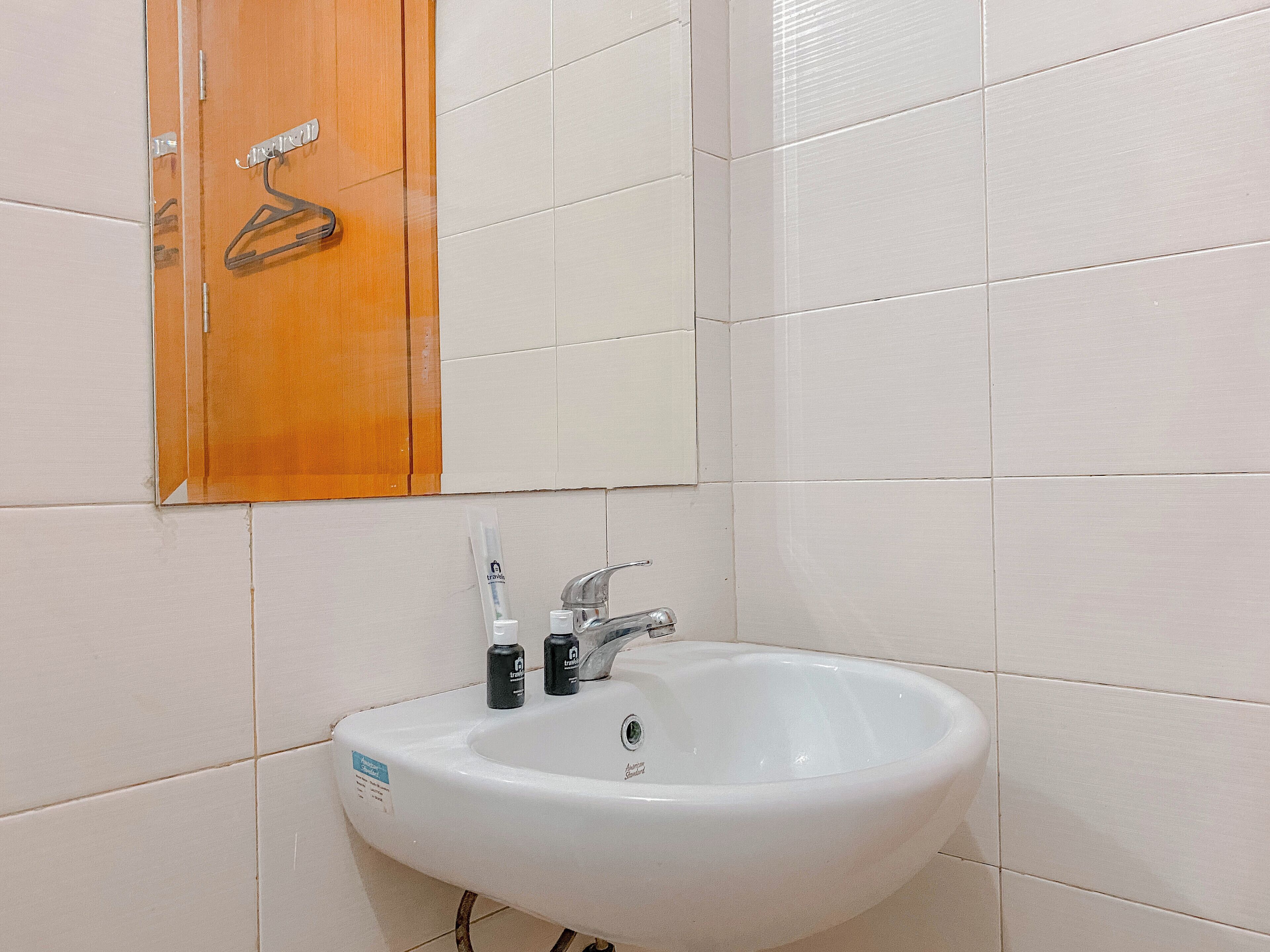 Un baño con un lavamanos blanco, un espejo y un mueble de madera.