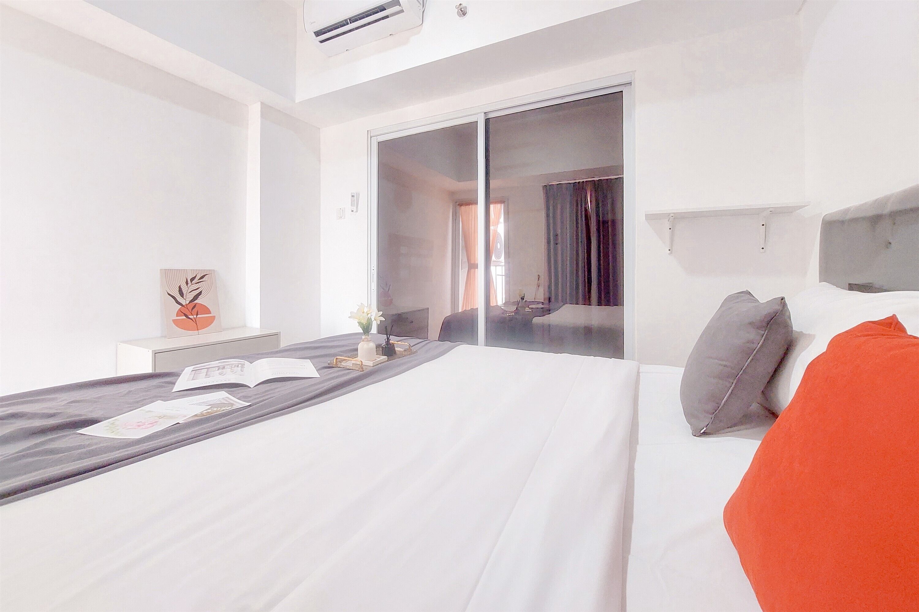 Quarto de hotel moderno com uma cama grande, uma mesa de cabeceira, porta de correr de vidro e vista para o exterior.