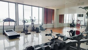 A gym with cardio machines, weightlifting equipment, and large windows. - Good Studio And Comfortable 1Br At Tamansari Bintaro Mansion Apartment (South Tangerang)