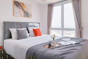 Relax in a spacious room with a large bed, city views, and elegant artwork.
