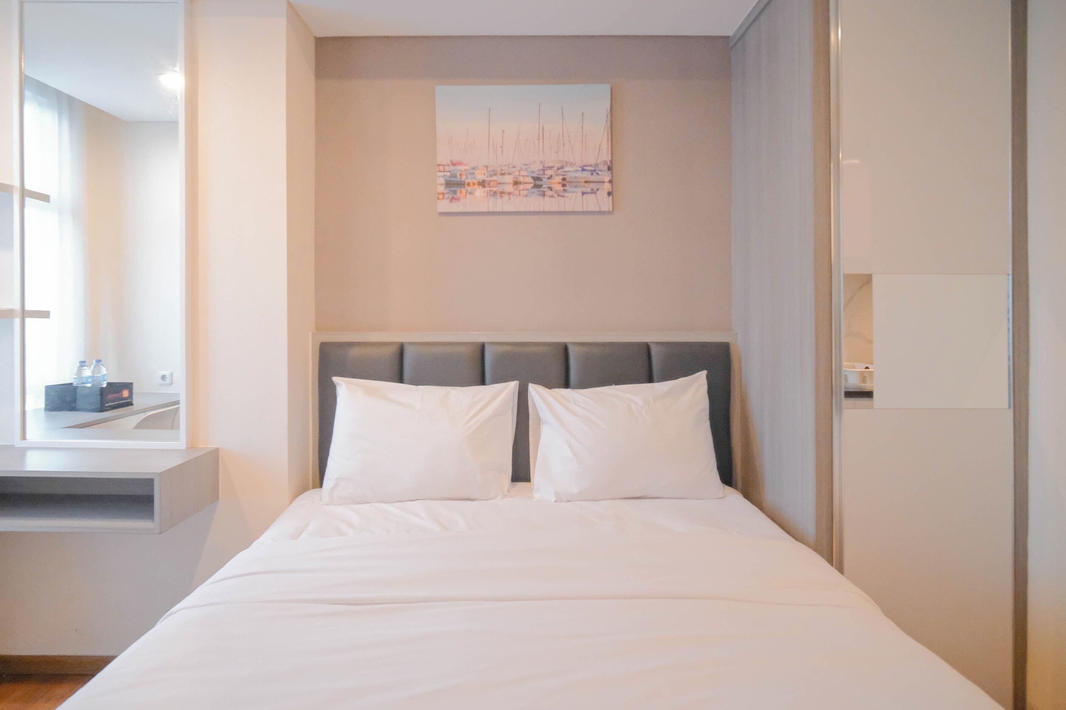 A modern hotel room with a large bed, a headboard, a flat-screen TV, and a painting on the wall.