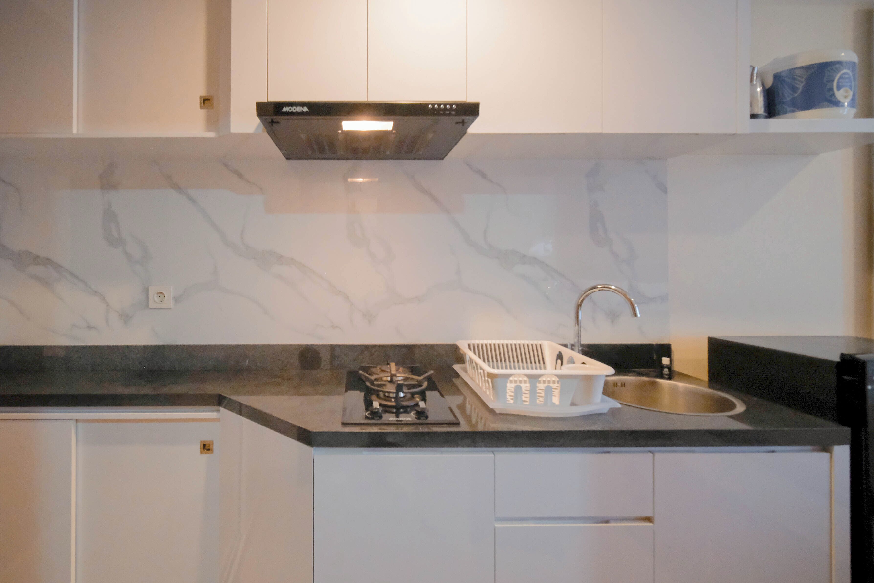 A kitchen with a gas stove, a sink, and white cabinets.