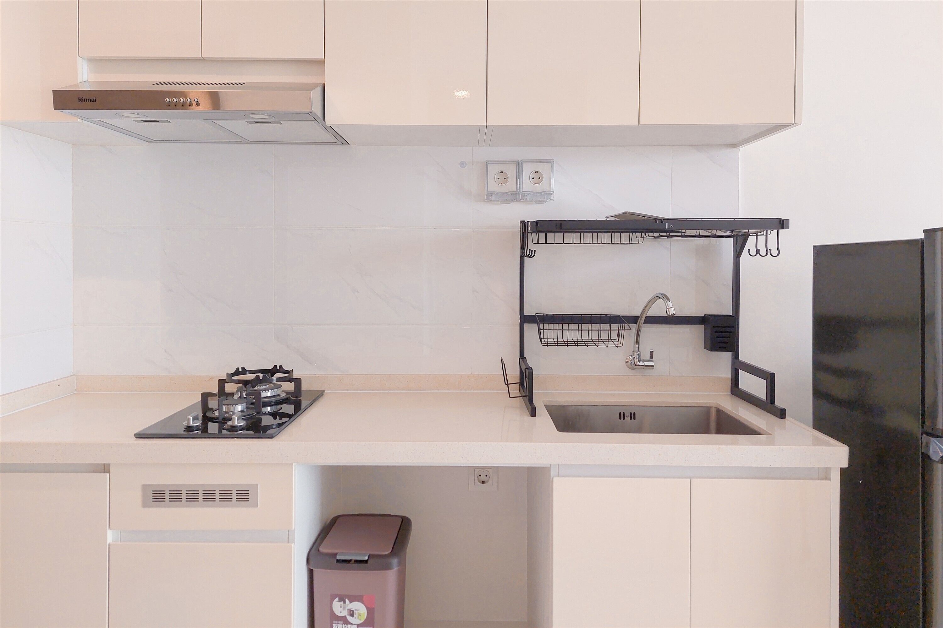 A modern kitchen with a gas stove, sink, and stainless steel refrigerator.