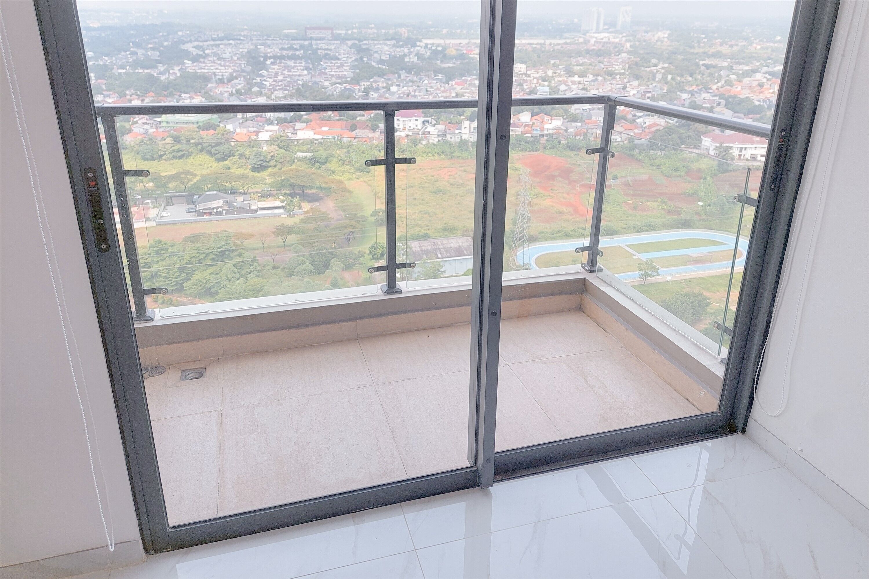 Un balcon doté d’une porte vitrée, offrant une vue sur un quartier résidentiel avec des maisons et de la verdure.
