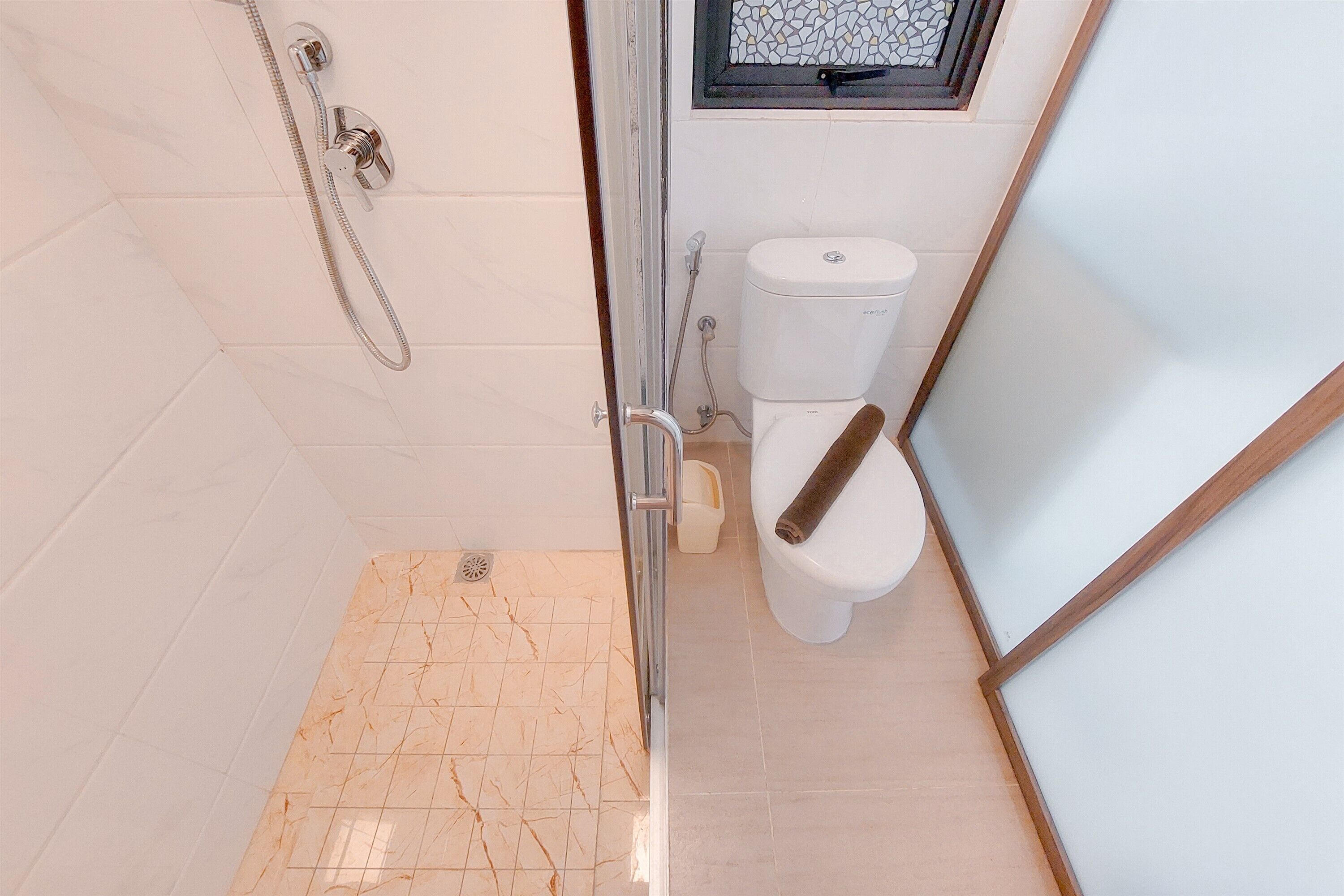 A bathroom with a shower, toilet, and a small window.