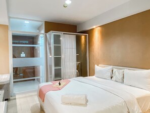 A hotel room with a large bed, a walk-in closet, and a sliding glass door leading to a balcony.