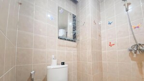 A bathroom with a toilet, a shower, and a mirror.