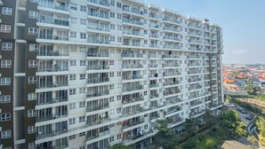 A multi-story residential building with balconies, large windows, and a view of a residential area. - Homey 1Br Apartment At Gateway Pasteur (Cimahi)