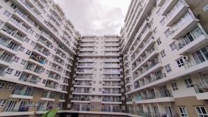 Um edifício residencial alto, com várias varandas e aparelhos de ar condicionado.