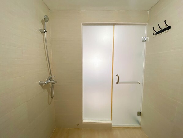 A bathroom with a shower, a door with a handle, and a towel rack on the wall.