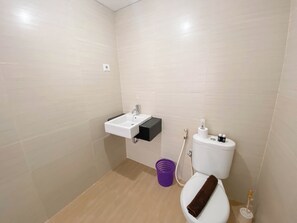 Bathroom features a white toilet, sink, and light beige tile walls.