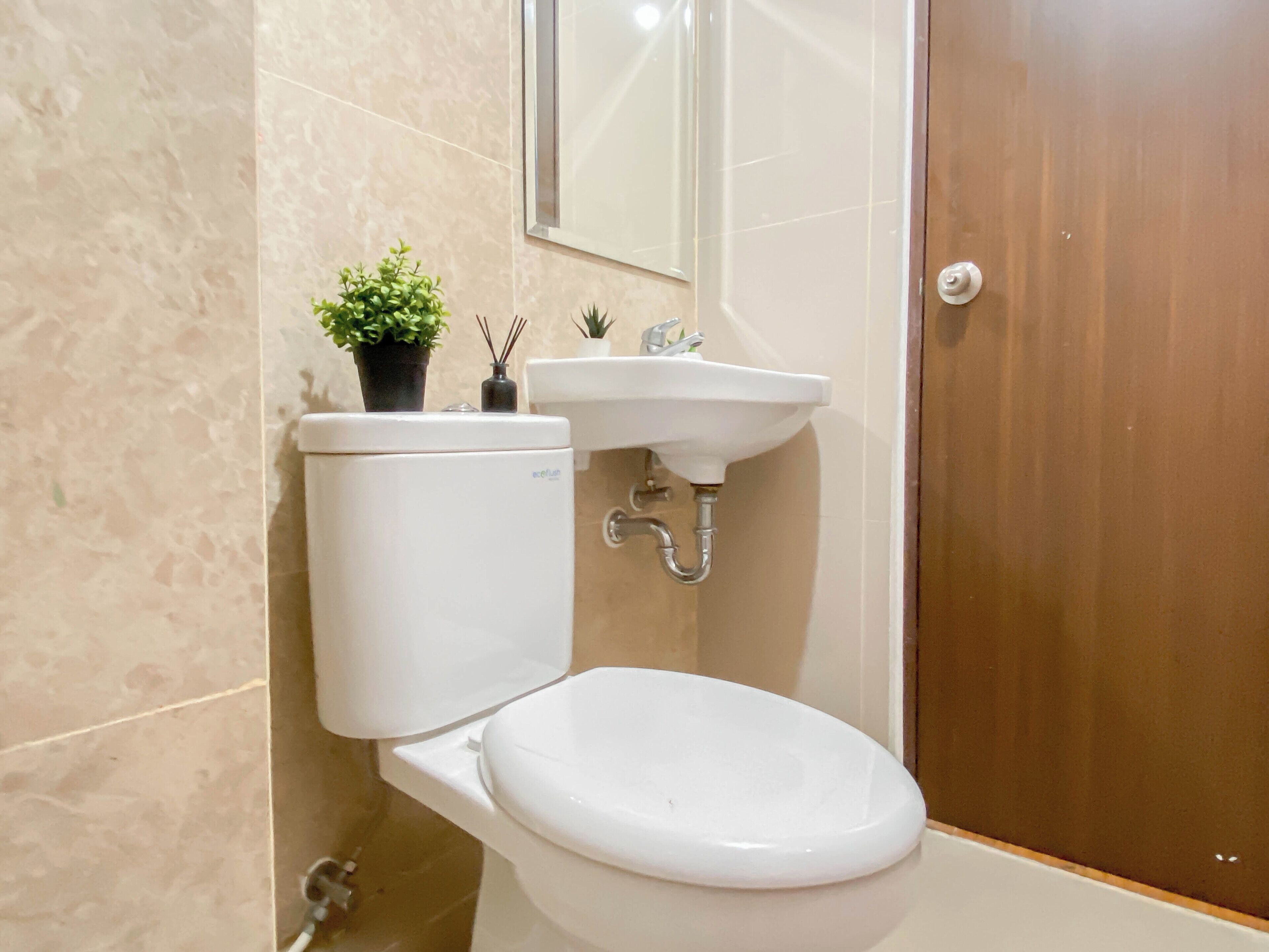 A bathroom with a toilet, sink, and mirror.