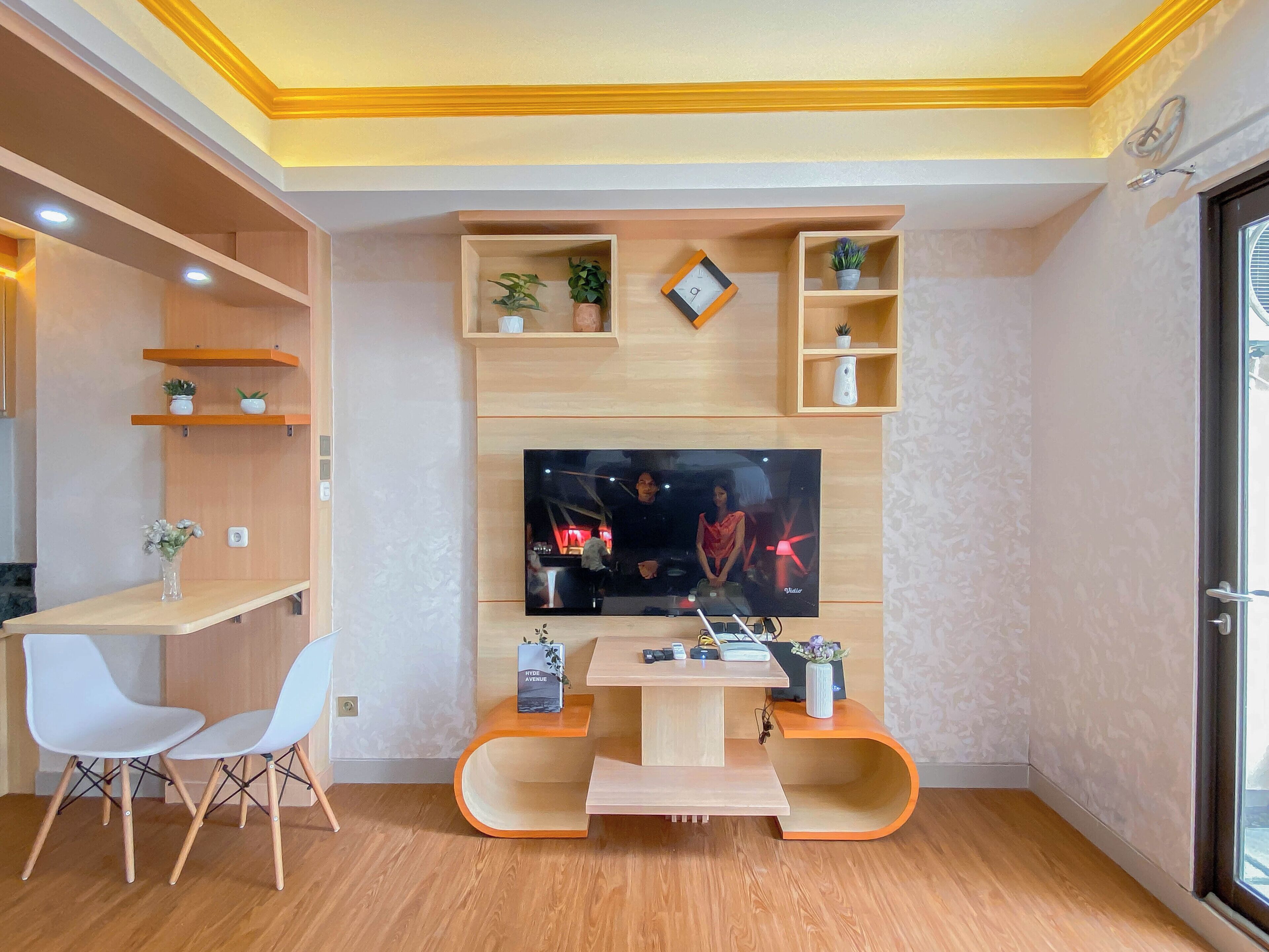 Ein modernes Wohnzimmer mit Flachbildfernseher, Holzregalen, einem Essbereich mit Stühlen und einem kleinen Tisch.