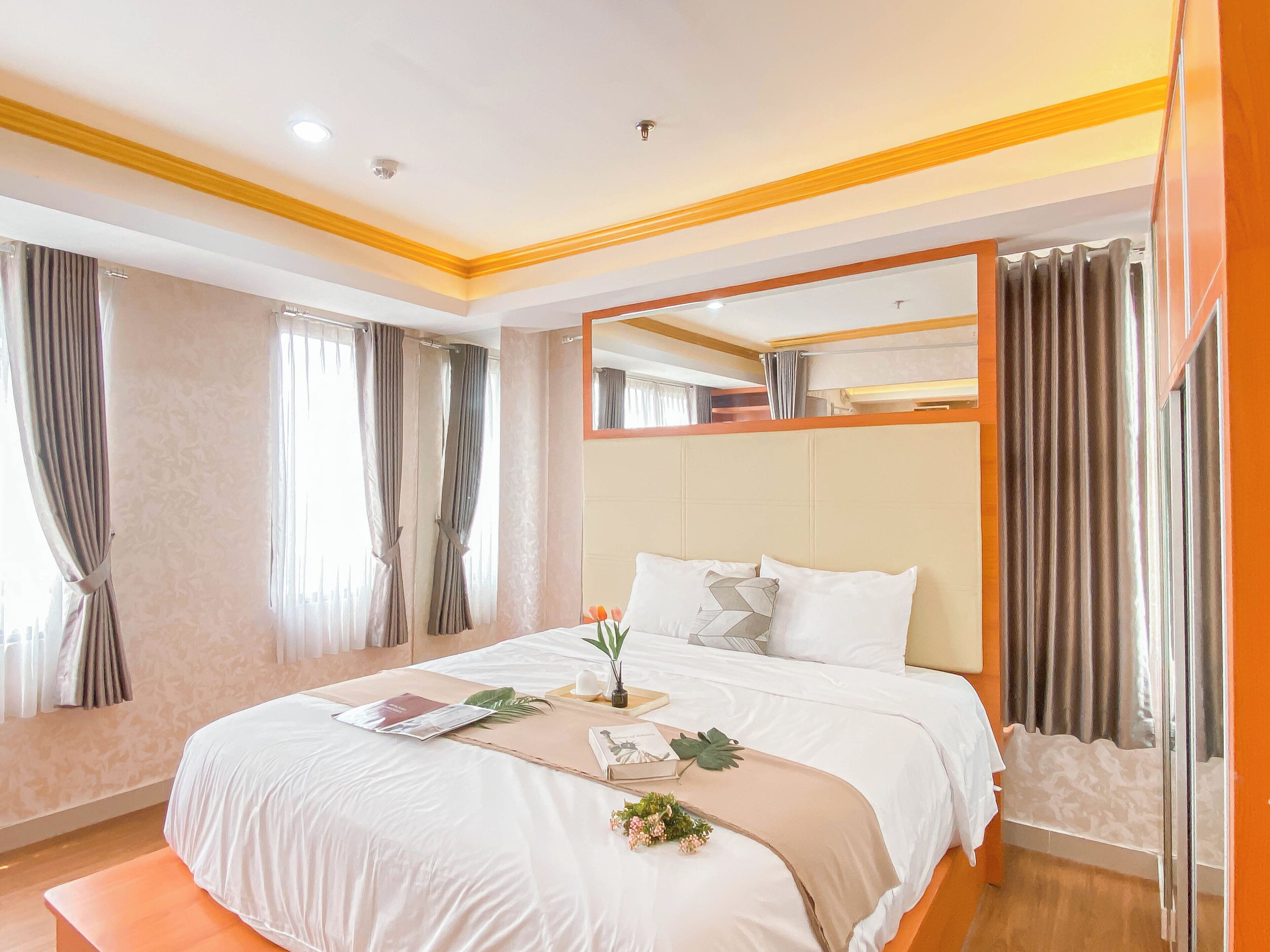 A hotel room with a large bed, a bedside table, a mirror, and curtains.