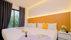 Habitación de hotel con una cama grande, una mesita de noche, una ventana con cortinas y vistas a zonas verdes.