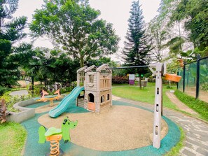 A playground with a slide, climbing structures, and a swing set. - Vimala Hills Villa Gadog Puncak 3Br For 12 Pax (Ciawi)