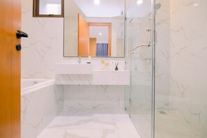 A modern bathroom with a glass-enclosed shower, a white marble sink, and a wooden door. - Vimala Hills Villa Gadog Puncak 3Br For 12 Pax (Ciawi)