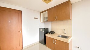 A compact kitchen with wooden cabinets, a stainless steel sink, and a black refrigerator.