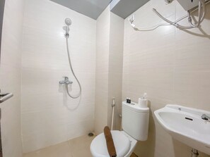 A bathroom with a toilet, a shower, and a sink. - Homey Designed 3Br At Gateway Pasteur Apartment (Cimahi)