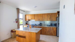 A modern kitchen with wooden cabinets, a granite countertop, and stainless steel appliances.