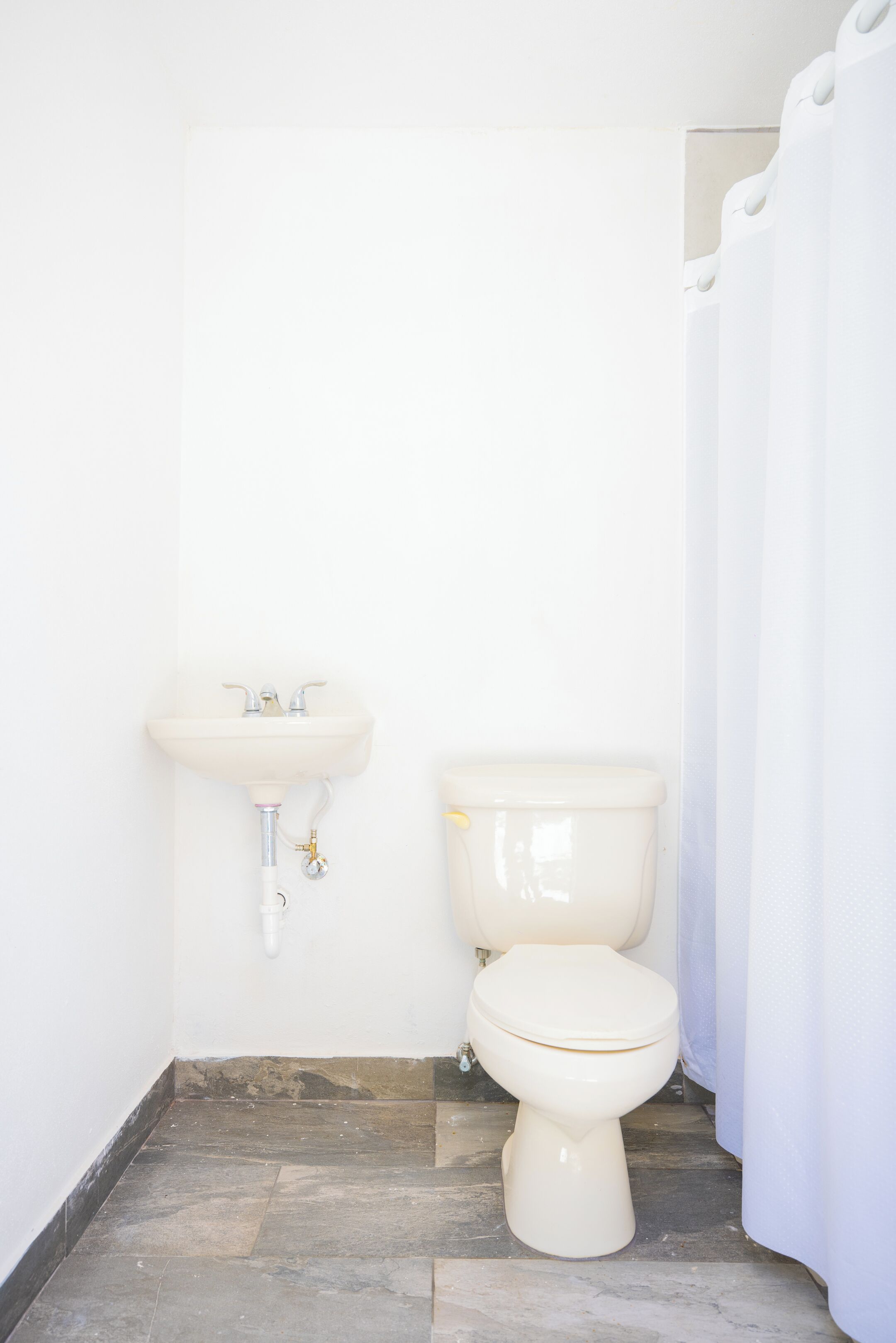 Ein kleines, weißes Badezimmer mit Waschbecken und Toilette.