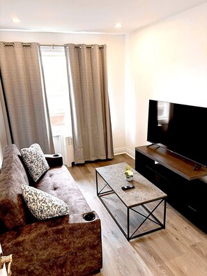 A modern living room with a sofa, coffee table, and a flat-screen TV.