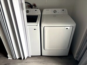 Uma lavanderia com duas máquinas de lavar roupa brancas e uma secadora.