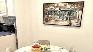 A dining area with a round table, four chairs, a cake, and a vase with flowers.