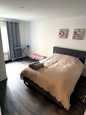 Quarto com cama, uma mesinha e uma cadeira.