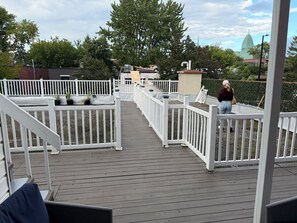 A wooden deck with white railings, potted plants, and a view of a church steeple.