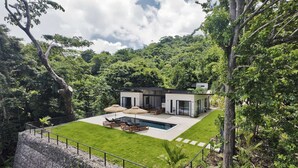 Ein modernes Haus mit Swimmingpool, umgeben von üppigem Grün.