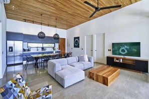 Un soggiorno moderno con un divano angolare grigio, un tavolino in legno e una TV su un mobiletto in legno.