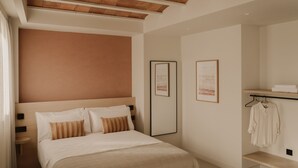 A hotel room with a bed, a wooden headboard, a bedside table, a wall-mounted shelf with a towel, and framed artwork on the wall. - Studio Apartment Pau Suites (La Vila Joiosa)