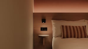 Ein modernes Hotelzimmer mit einem Bett, einem Nachttisch und einer Wandleuchte.