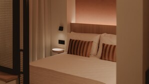 A bedroom with a bed, a nightstand, a lamp, and a window with curtains. - Superior Apartment Pau Suites (La Vila Joiosa)