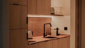 A modern kitchen with wooden cabinets, a countertop, a sink, and a kettle. - Superior Apartment Pau Suites (La Vila Joiosa)